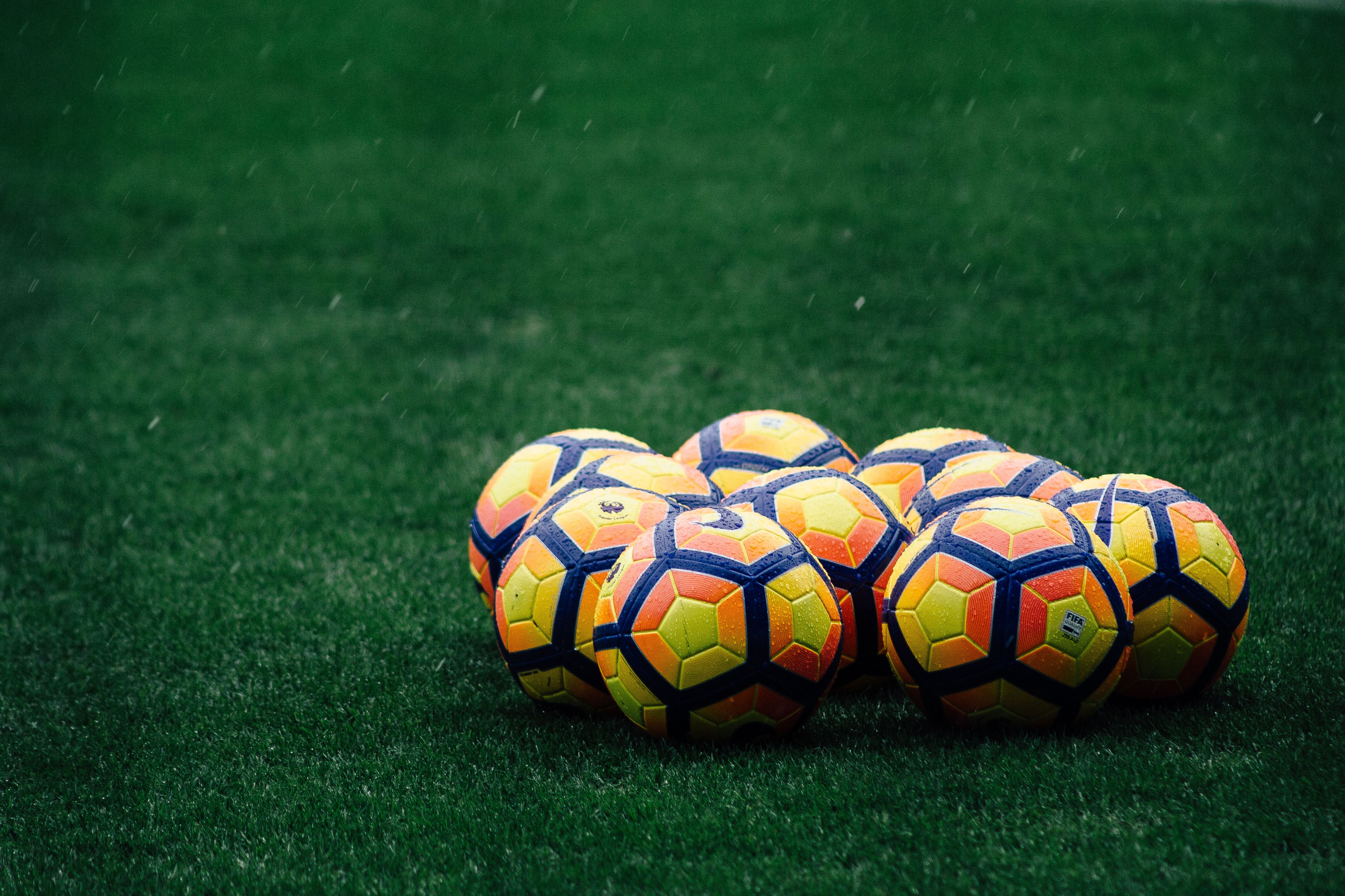 Group of soccer balls on green field.